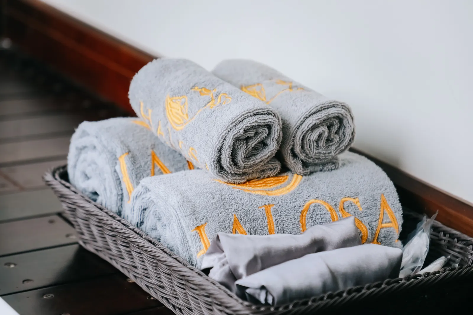 Neatly rolled towels with gold embroidery in a wicker basket